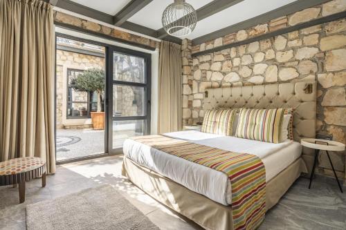 1 dormitorio con 1 cama grande y pared de piedra en Charming Flat near Hadrians Gate, en Antalya