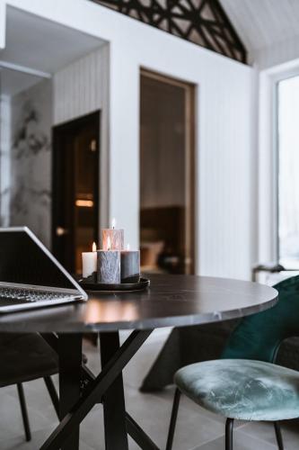 a table with a laptop and candles on it at Sniegi design cabin with sauna in Madona