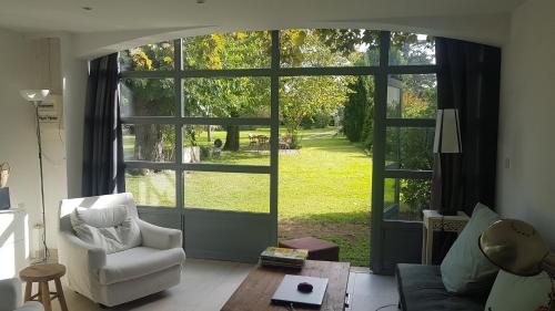 ein Wohnzimmer mit einem großen Fenster und einem Stuhl in der Unterkunft Gîte cocooning avec piscine in Bougé-Chambalud