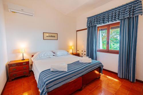 a bedroom with a bed with blue curtains and a window at Tenuta Delle Ripalte in Capoliveri
