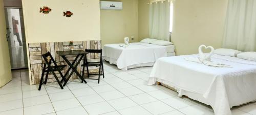 Cette chambre comprend deux lits, une table et des chaises. dans l'établissement Pousada Vila Bela, à Ipojuca