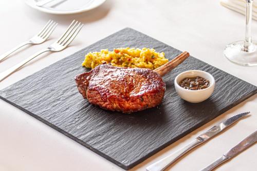 a steak on a black plate with rice and sauce at Mirador del Lago Hotel in El Calafate