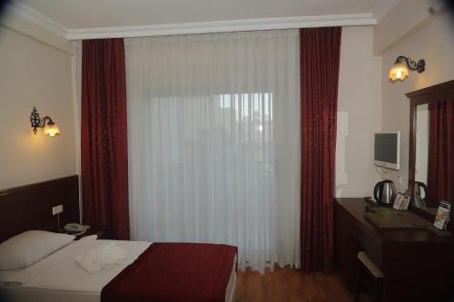 a bedroom with a bed and a window with red curtains at STELLA HOTEL&Spa ALL INCLUSIVE in Kemer
