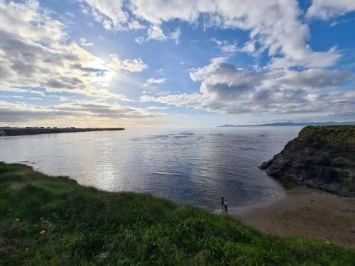 a person standing on a beach near a body of water at Bundoran Seaside Stays House - WiFi, large spacious home in Bundoran