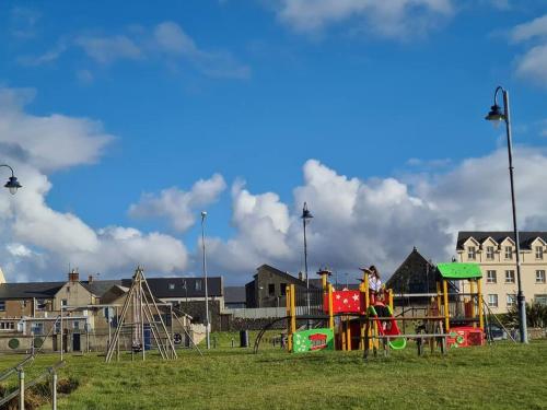 a playground in a park with people playing on it at Bundoran Seaside Stays House - WiFi, large spacious home in Bundoran