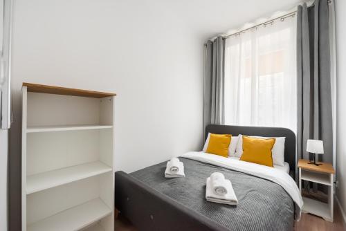 a bedroom with a bed with yellow pillows and a window at Chmielna Warsaw City Centre Apartment in Warsaw