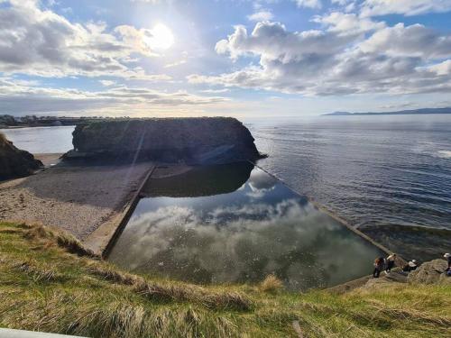 a reflection of a rock in the water on a beach at Bundoran Seaside Stays House - WiFi, large spacious home in Bundoran