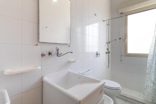 La salle de bains blanche est pourvue d'un lavabo et de toilettes. dans l'établissement Appartamento vista mare Scoglitti, à Scoglitti
