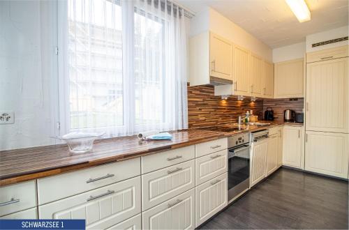 a kitchen with white cabinets and a large window at Chalet Schwarzsee by Arosa Holiday in Arosa