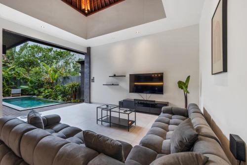 ein Wohnzimmer mit einem großen Sofa und einem Fernseher in der Unterkunft New modern & minimalist Villa in Canggu