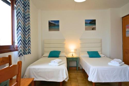 two twin beds in a room with a table at Apartamentos Vistalmar Mallorca in Cala Figuera