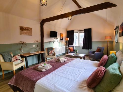 a bedroom with a large bed and a living room at B&B De Kan Hoeve in De Veenhoop