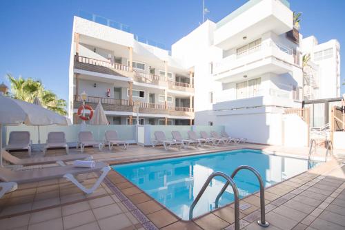 un hotel con piscina frente a un edificio en Apartamentos Tarahal, en San Agustín