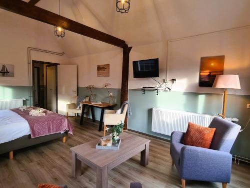 a bedroom with a bed and a couch and a table at De Kan Hoeve appartementen in De Veenhoop