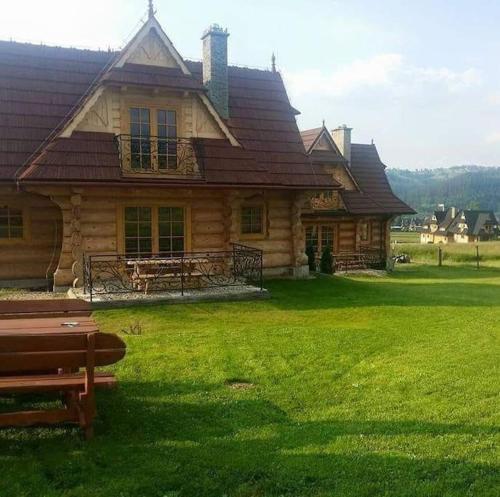 a log house with a bench in front of it at Przytulne Domki u Kantora nr 2 in Poronin