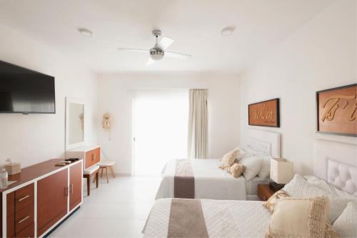 a white bedroom with a bed and a tv at Saastah Hotel Boutique in Valladolid