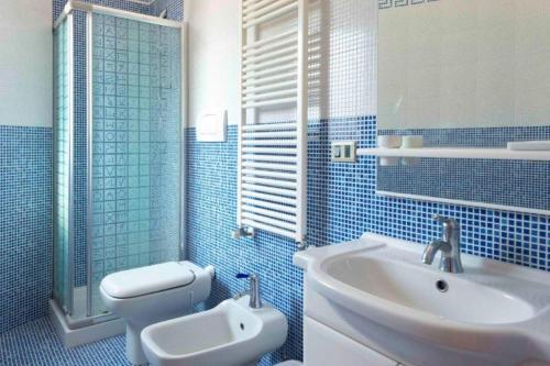 ein blau gefliestes Bad mit einem Waschbecken und einem WC in der Unterkunft Villa Montedoro Luxury in Noci