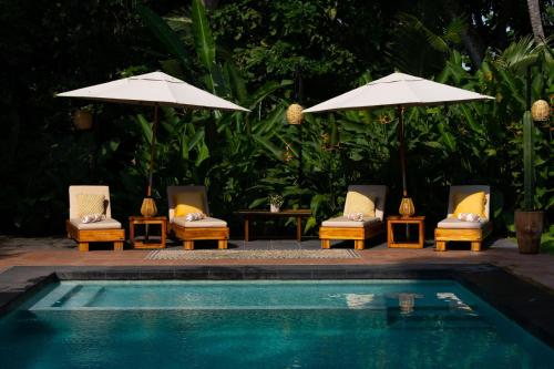 a group of chairs and umbrellas next to a pool at La Paranera Hotel & Relax in Comala