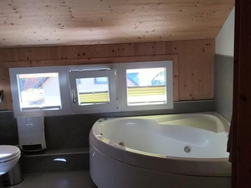 ein Badezimmer mit einer großen Badewanne und zwei Fenstern in der Unterkunft Spatzennest in Hohentauern