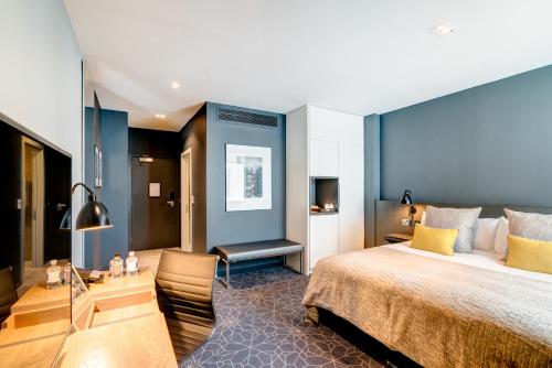 a bedroom with a large bed with a blue wall at Apex City of Bath Hotel in Bath