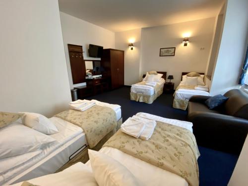 a hotel room with three beds and a couch at Hotel Patria Zakopane Centrum in Zakopane