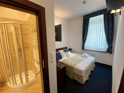 a hotel room with a bed and a shower at Hotel Patria Zakopane Centrum in Zakopane