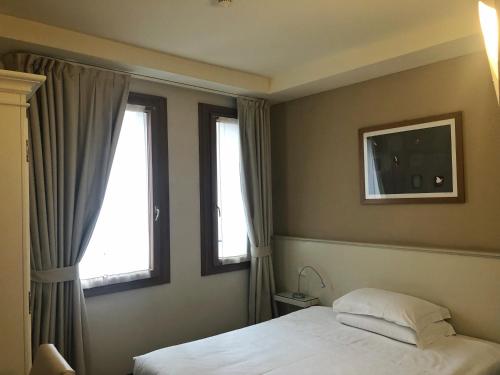 a bedroom with a bed and two windows at Hotel Canon d'Oro in Conegliano