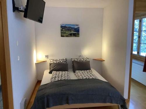 a bedroom with a bed with a tv on the wall at BnB Försterlodge in Schwarzsee