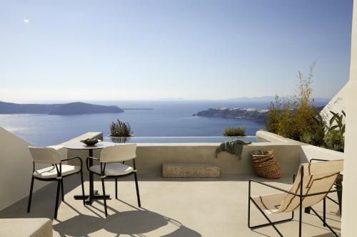 un patio con mesa y sillas con vistas al océano en Atoles Retreat, en Imerovigli