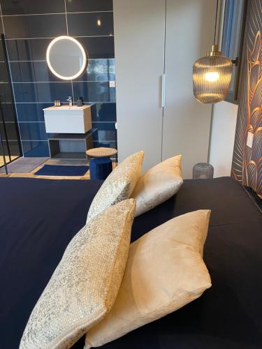 - un ensemble d'oreillers sur un lit avec lavabo dans l'établissement Les Hutins, à Gex