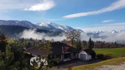 a house on a hill with mountains in the background at Haus Löger Apartments Pyhrn Priel in Windischgarsten