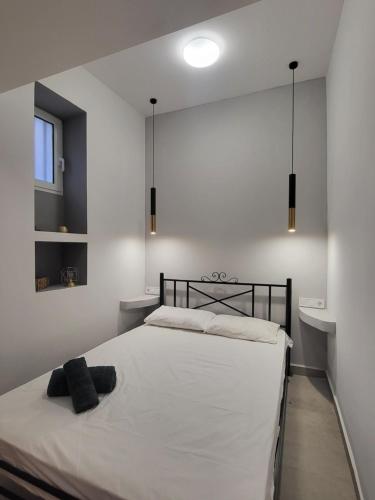 ein Schlafzimmer mit einem weißen Bett mit einem schwarzen Kopfteil in der Unterkunft Evangelia's Cozy House in Ermoupoli