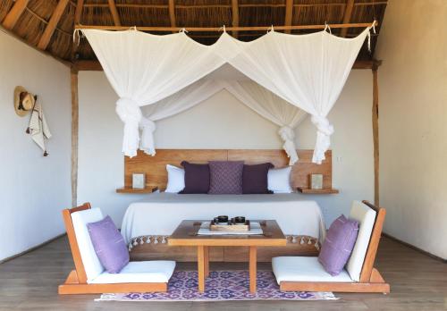 a bedroom with a bed with a table and two chairs at Xinalani Retreat Mexico in Qumiste