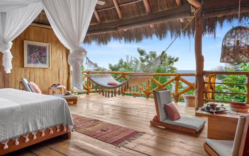 a bedroom with a hammock and a view of the ocean at Xinalani Retreat Mexico in Qumiste