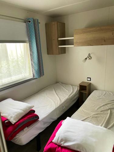 2 camas en una habitación pequeña con ventana en Bungalow de 3 chambres avec piscine partagee terrasse amenagee et wifi a Saint Cyprien a 3 km de la plage, en Saint-Cyprien
