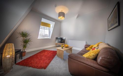 a living room with a brown couch and a red rug at Loft Apartment, Keswick in Keswick