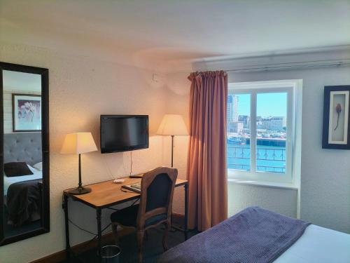 a hotel room with a desk and a bed and a window at Logis HOTEL RESTAURANT La Régence in Cherbourg en Cotentin