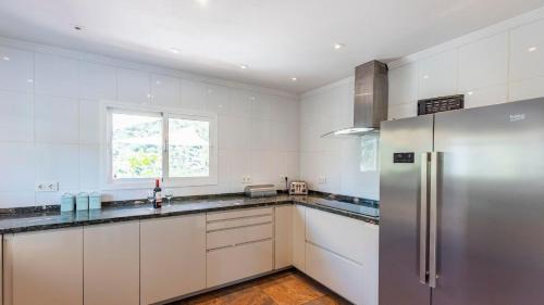 a kitchen with white cabinets and a stainless steel refrigerator at Casa Holly Comares by Ruralidays in Comares