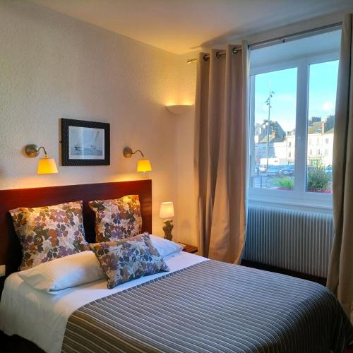 a bedroom with a bed with a large window at Logis HOTEL RESTAURANT La Régence in Cherbourg en Cotentin