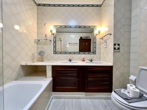 y baño con bañera, lavabo y espejo. en Vilamoura Brightness With Pool by Homing en Vilamoura