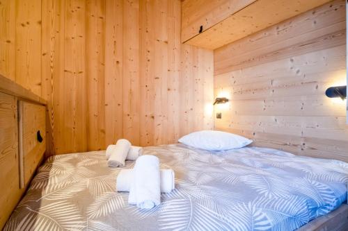 un letto in una camera di legno con asciugamani di Comfortable studio with balcony - Huez - Welkeys a LʼHuez