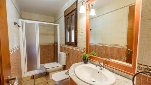 a bathroom with a sink and a toilet and a mirror at Lake view villa Iznájar by Ruralidays in Iznájar