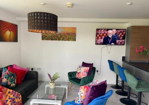 a living room with a couch and chairs and a tv at Contemporary, Cosy & Homely 2 Bed Apartment with High-Speed WIFI, Terrace & Free Parking overlooking Stourbridge Common Park & Coldham's Brook in Cambridge