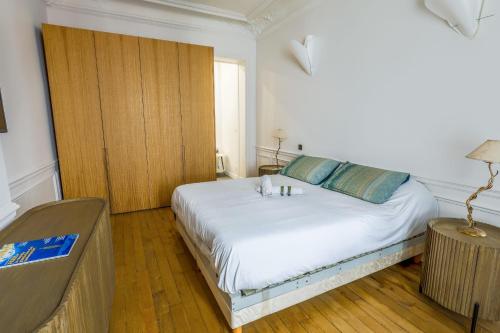 - une chambre avec un lit blanc et une porte en bois dans l'établissement Appartement du Pilot - Welkeys, à Neuilly-sur-Seine