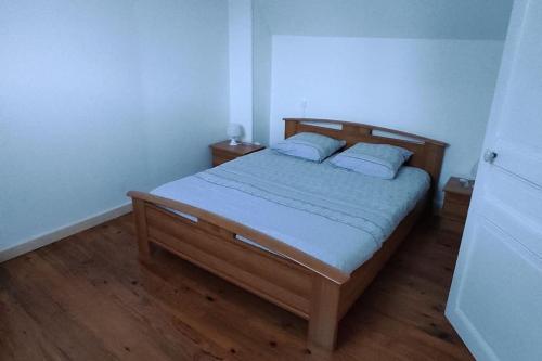 a bedroom with a wooden bed with two pillows at maison de ville pour 6 personnes in Montdidier