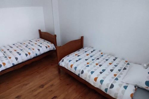 two twin beds in a room with wooden floors at maison de ville pour 6 personnes in Montdidier