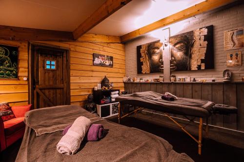 B&B en Wellness de Waalhoeve في Angerlo: غرفة نوم بسريرين في غرفة بجدران خشبية