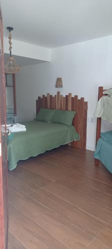 a bedroom with a green bed with a wooden headboard at Pousada Neptun in Conde