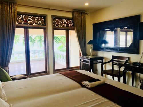a bedroom with a large bed and a desk and windows at Keraton Krakatoa in Banten