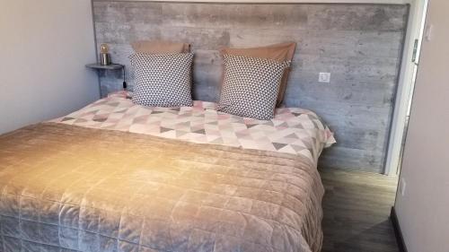 Schlafzimmer mit einem Bett mit einem Kopfteil aus Holz in der Unterkunft Gîte l'ancienne forge 4 adultes et 2 enfants in Louvetot